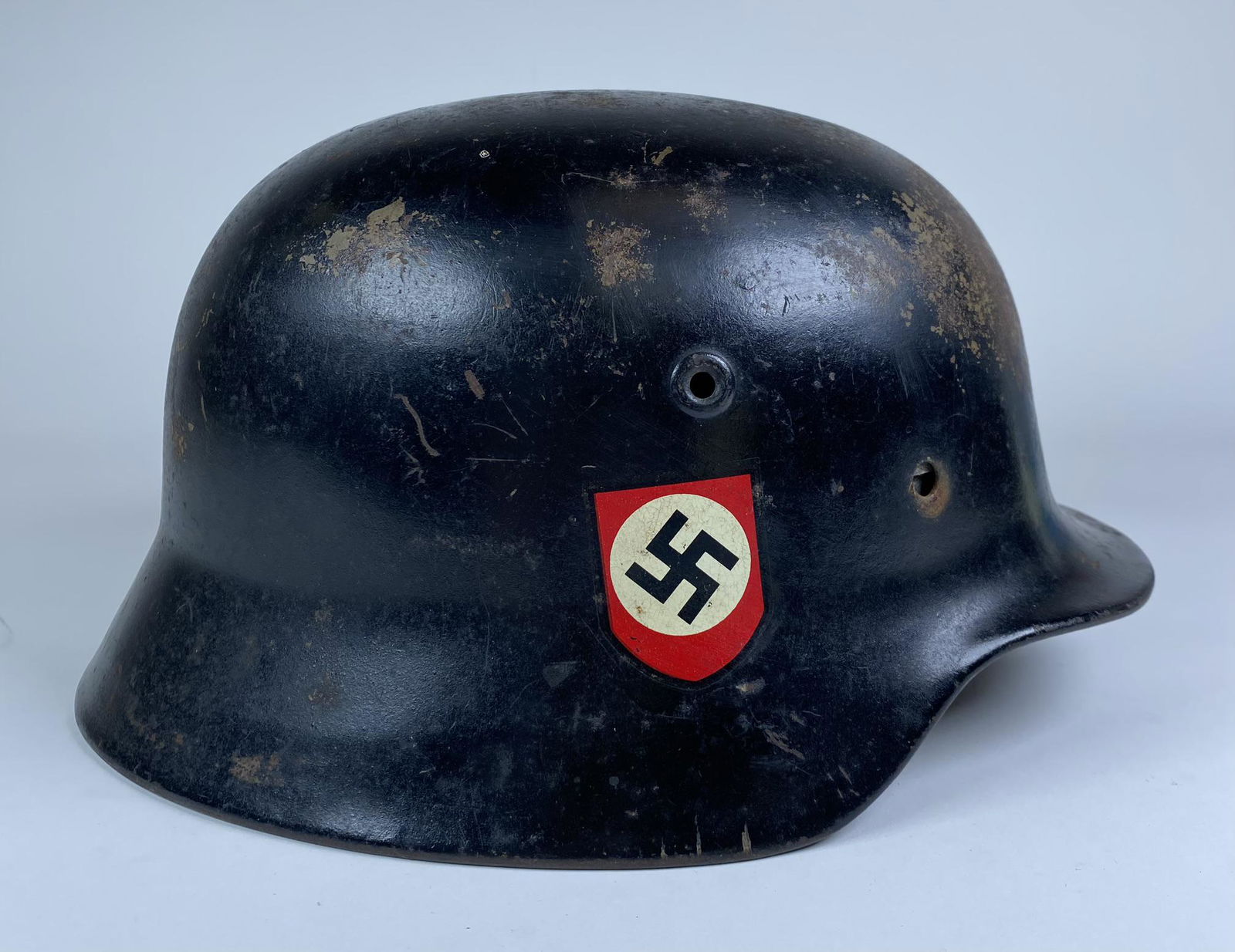 WWII GERMAN NAZI ERA M-40 HELMET: GREEN INTERIOR WITH BLACK OVERPAINT ON EXTERIOR. POLITICAL AND SS DECALS APPLIED TO EXTERIOR ON WRONG OPPOSING SIDES. MISSING TWO RIVETS. SIZE 58 LINER PRESENT.