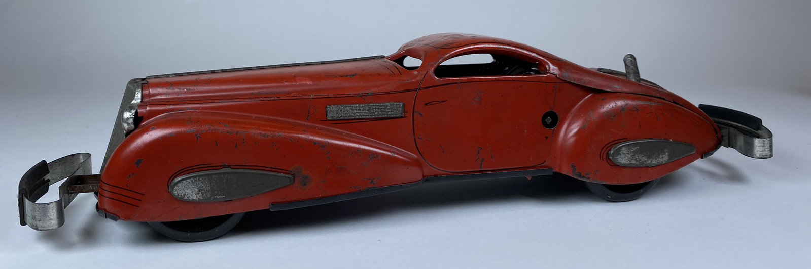 MARX RED REVERSING STREAMLINE CAR.: WORKING MARX REVERSING STREAMLINE CAR. BUMPER IMPACT REVERSES THE CAR DIRECTION. LARGE TIN WINDUP BY MARX. NO KEY. DESIRABLE. 16" L.