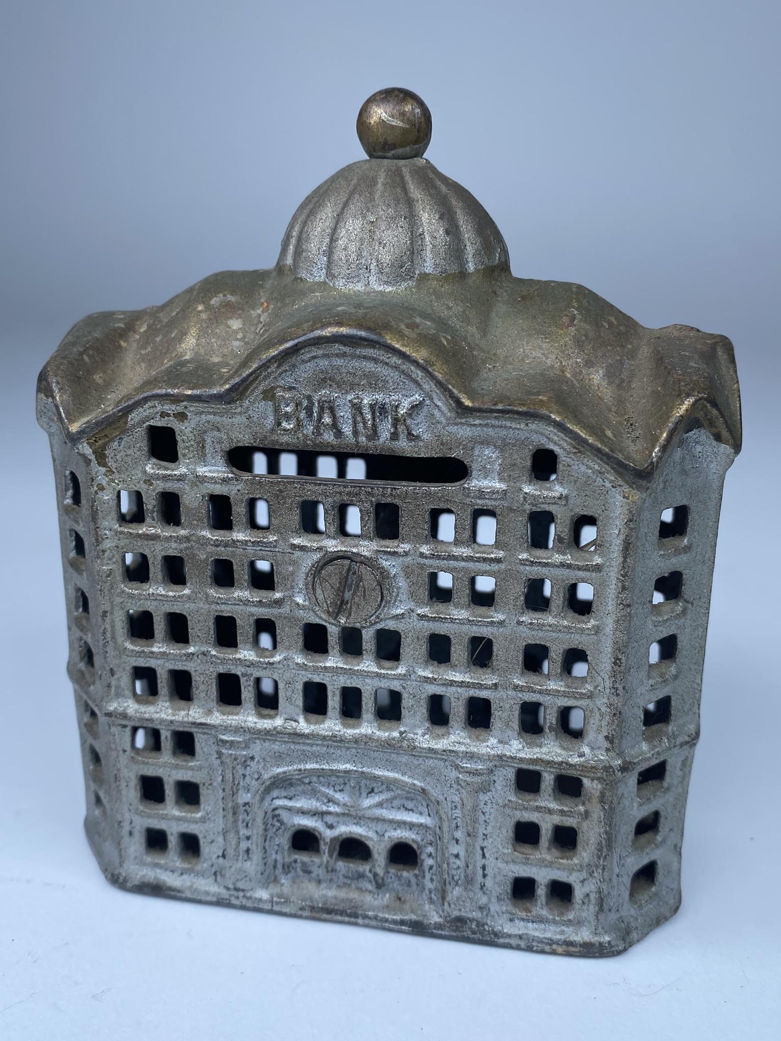 AC WILLIAMS STILL BANK: CAST IRON STILL BANK BY AC WILLIAMS. STRONG GOLD AND SILVER PAINT. 5" H X 4" W,