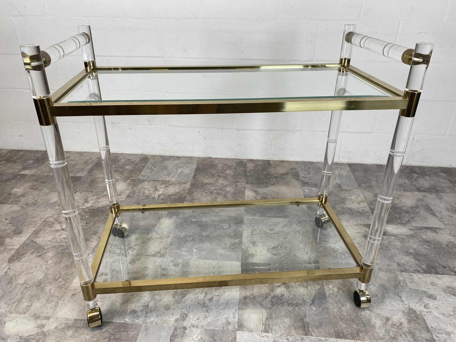 MANNER OF CHARLES HOLLIS JONES TEA CART: LUCITE AND BRASS FITTED TEA CART HAVING TWO BEVELED GLASS SHELVES. VERY MINOR WEAR TO METAL SURFACES. 34"X36"X18"