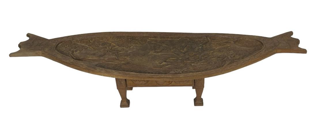 RENGUUL R. SULIAL CARVED TABLE: RENGUUL R. SULIAL, PALAU, C.1981. HAND CARVED TABLE OR TRAY ON STAND. BATTLE MOTIF. TOP IS 13"X44", 11"H