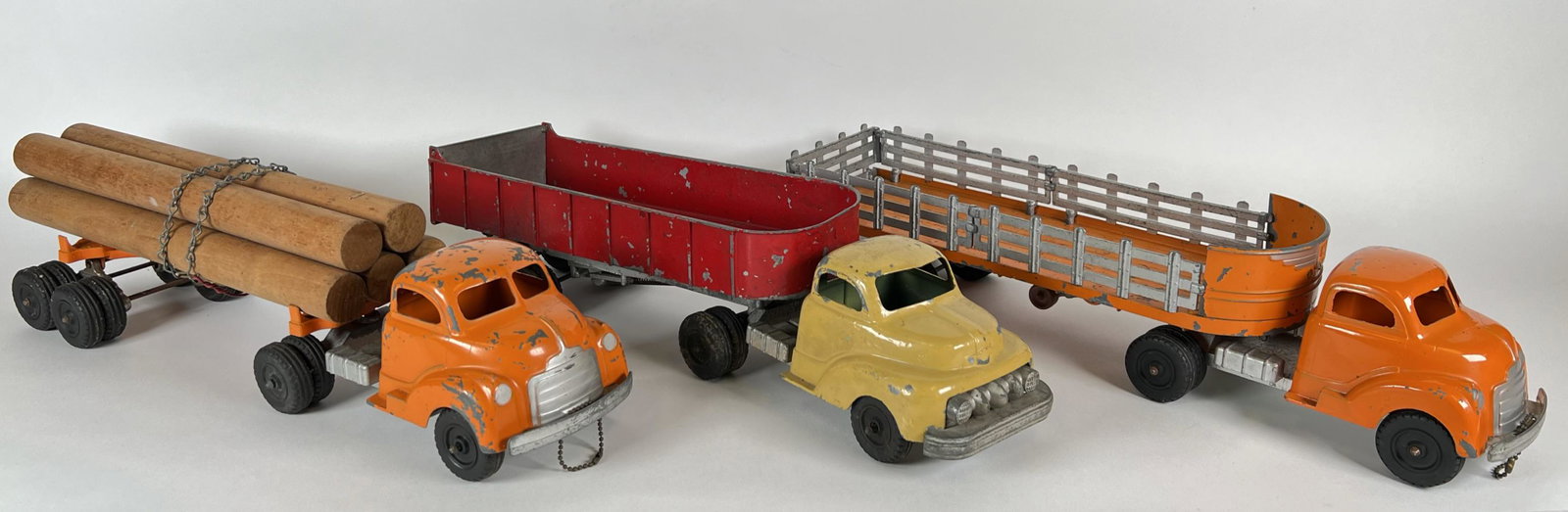 HUBLEY TOYS TRANSPORTER TRUCKS: STAKE SIDE HAULER, BED HAULER AND LOG HAULER. APPROX. 18"L
