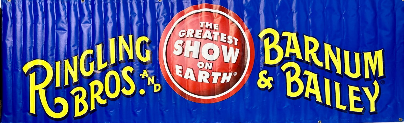 RINGLING BROS. BARNUM BAILEY CIRCUS BANNER: LARGE VINYL BANNER IS 10 FEET LONG AND BEARS THE RBBB LOGO AND TITLE ON A BLUE FIELD. GROMMETS FOR DISPLAY. 120"X40"