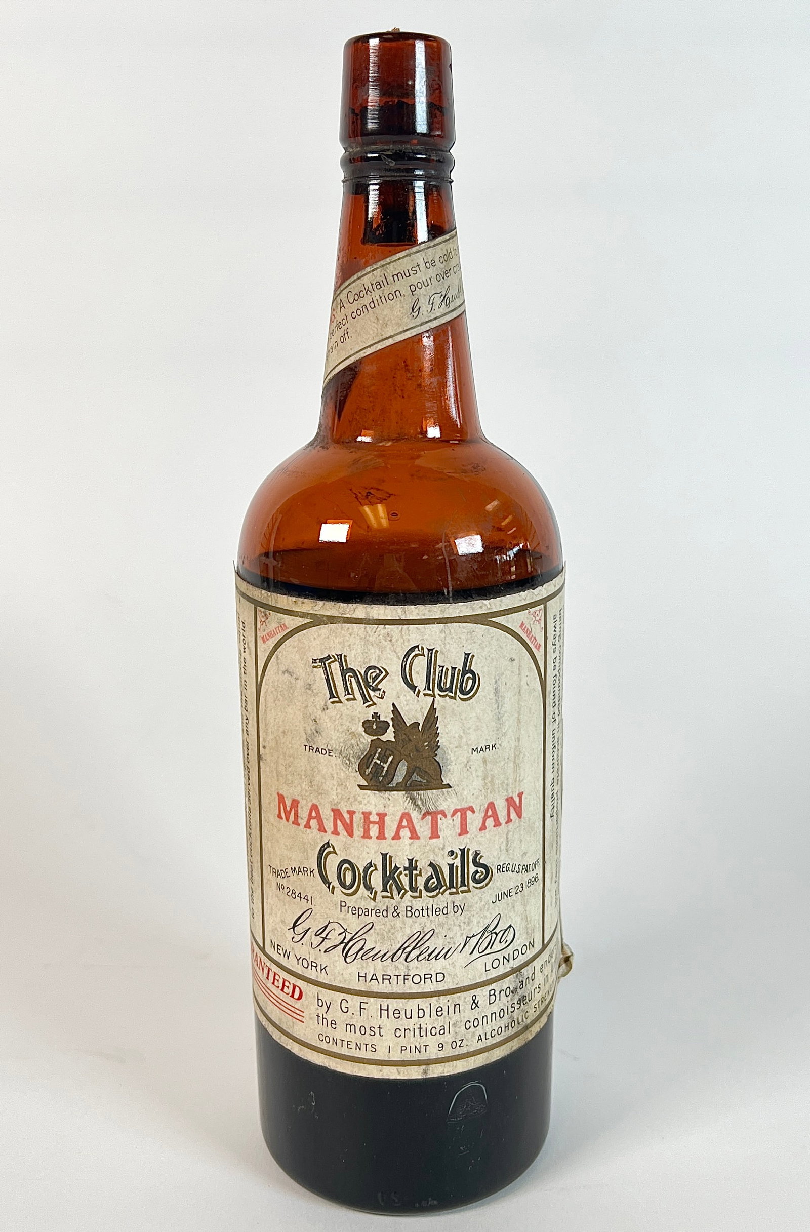 PRE-PROHIBITION HEUBLEIN WHISKY COCKTAIL: C.1900, NEARLY FULL, ORIGINAL GRAPHIC WRAPPER AND COPY OF VICTORIAN AD FOR THIS PRODUCT. SLIGHT VOLUME LOSS DUE TO LEAKAGE; CORK IS REPLACED, WITH ORIGINAL LEFT IN PLACE BENEATH REPLACEMENT. ORIGINAL 