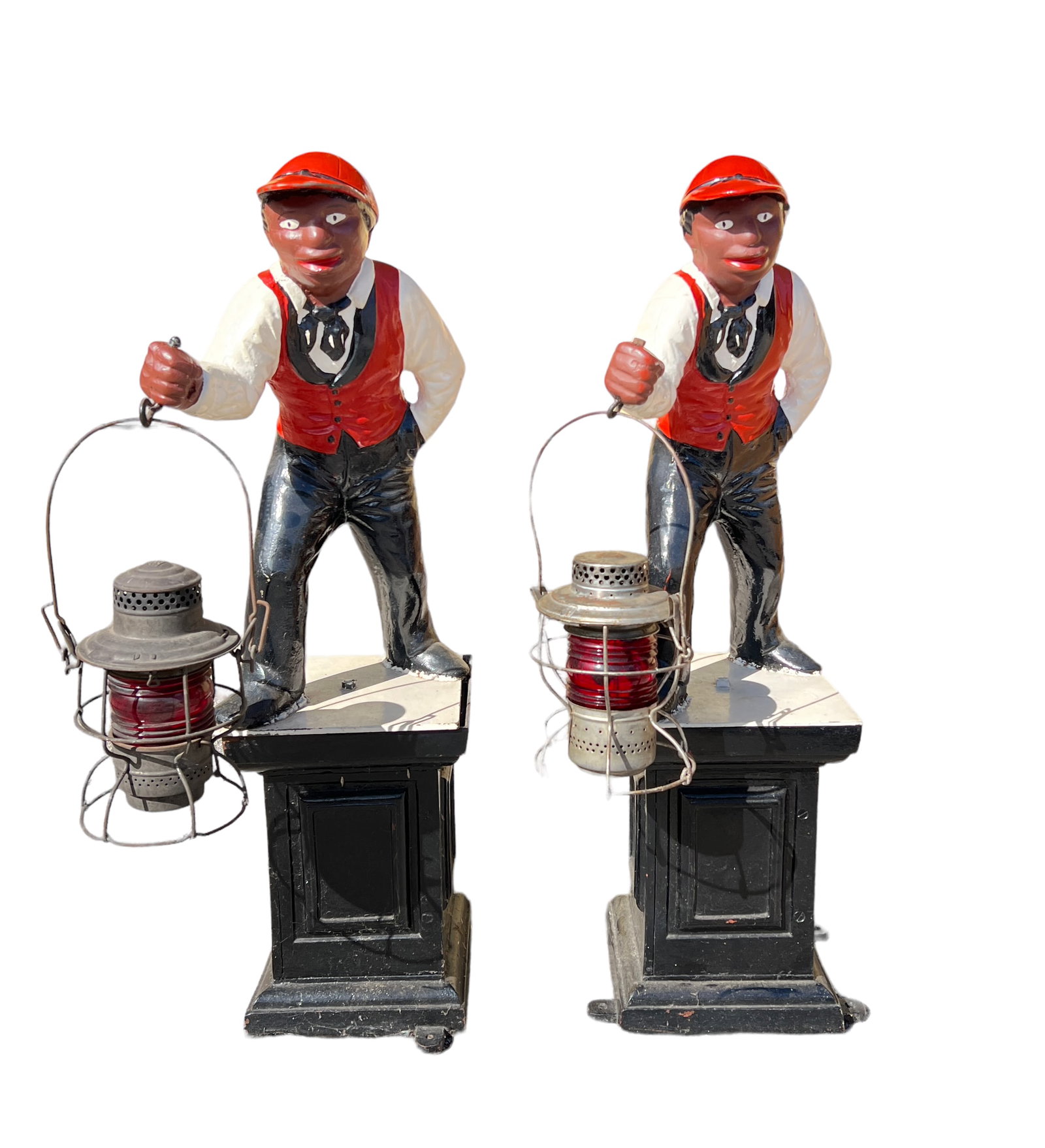 JOCKO LAWN JOCKEY PAIR: PAIR OF CAST IRON LAWN JOCKEYS, EACH WITH RED LENS RAILROAD LANTERNS. 39"H