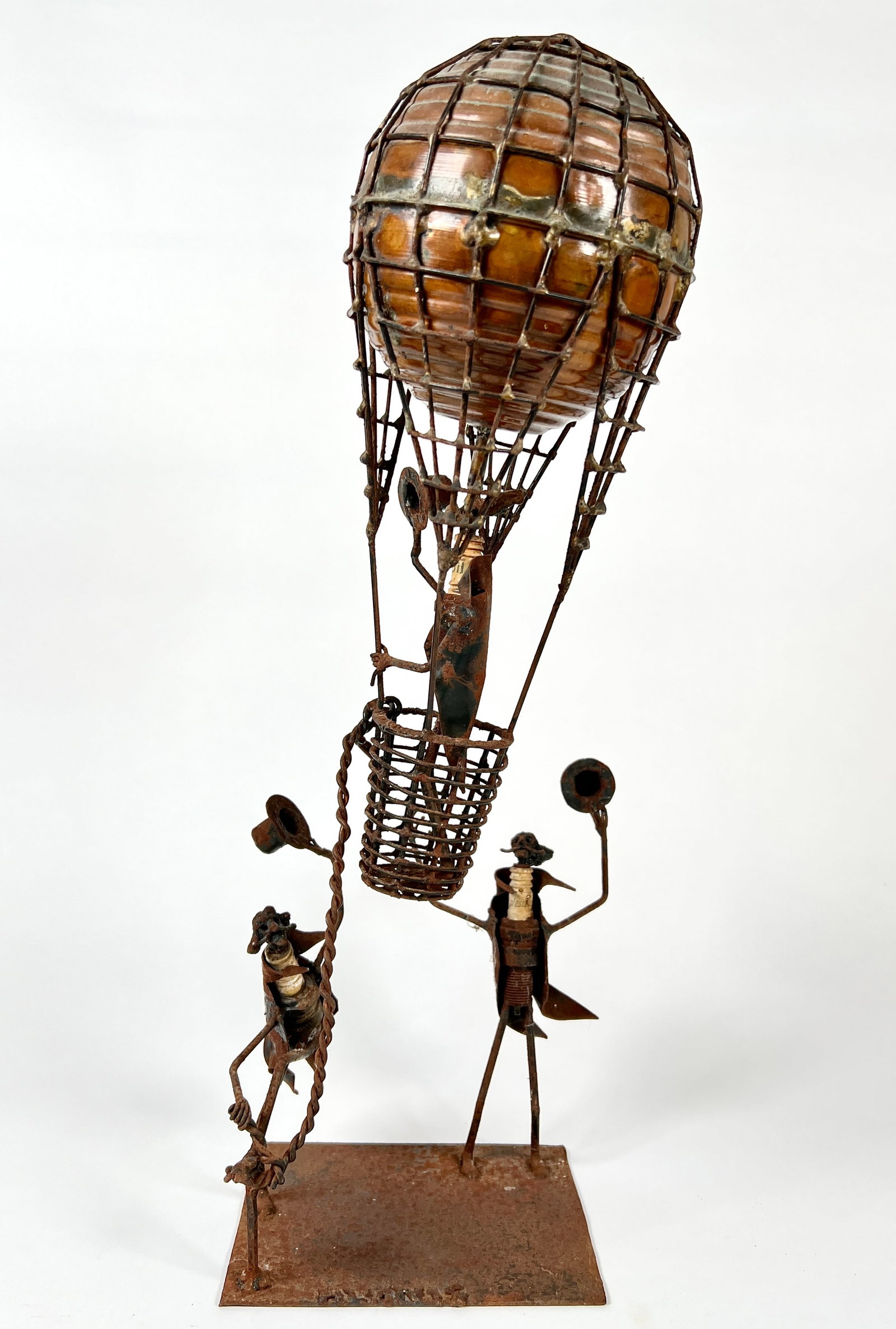 METAL FOLK ART SCULPTURE: SPARK PLUG FIGURES SENDING OFF A HOT AIR BALLOON. SIGNED. 18"