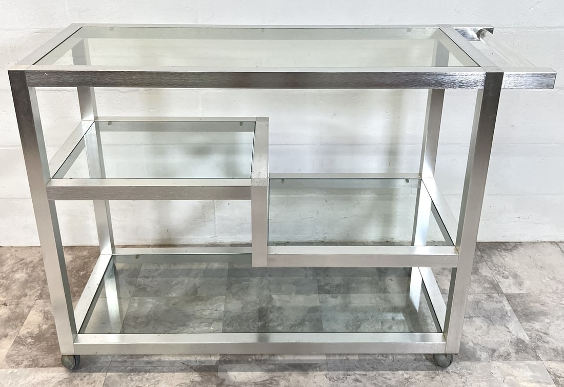 CHROME TROLLEY SERVING CART: BRUSHED ALUMINUM WITH ACRYLIC HANDLE, GLASS INSERTS. SCRATCHES AND WEAR TO ALL GLASS. 46"X18"X34"