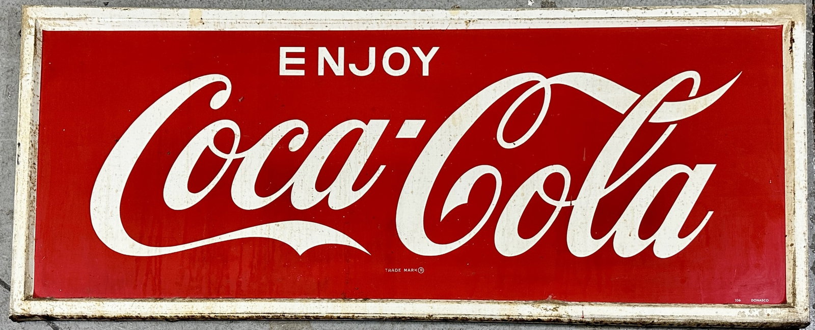 ENJOY COCA-COLA SST TIN SIGN: LARGE ADVERTISINGCOCA-COLA SINGLE SIDED TIN SIGN, FLANGE EDGES. #336 DONASCO. SCATTERED PITTING AND TONING. 24"X60"