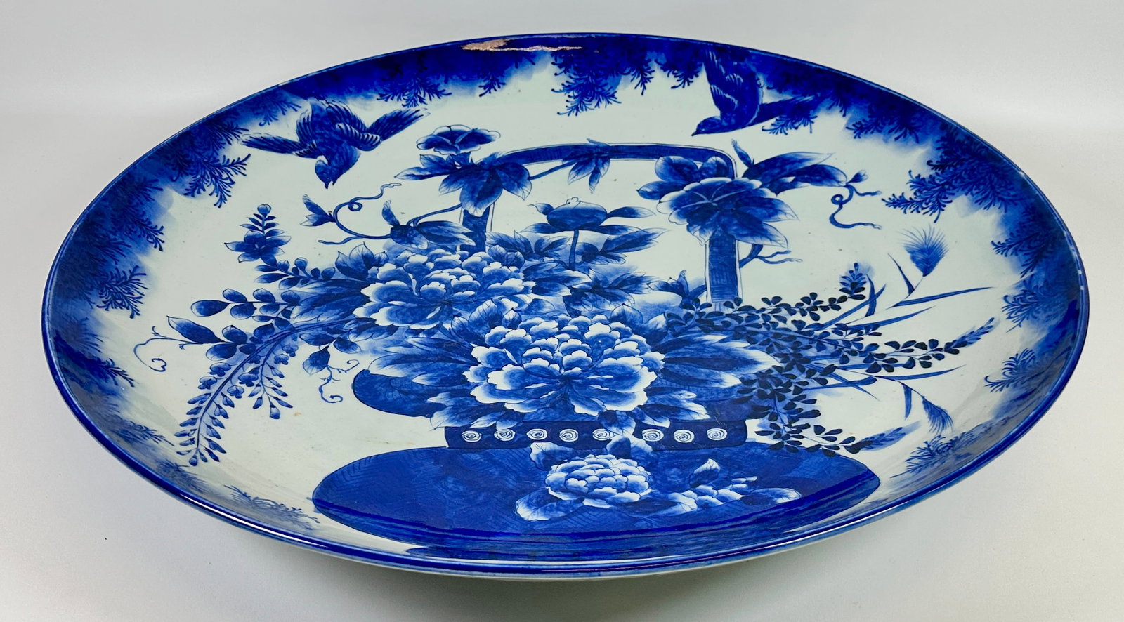 LARGE JAPANESEE IMARI PORCELAIN PLATE: COBALT DESIGNS. SIGNED. HAS A SMALL EDGE FRACTURE, VISIBLE FROM THE UNDERSIDE. 25"DIA. THIS ITEM REQUIRES THIRD PARTY SHIPPING/TRANSPORTATION.