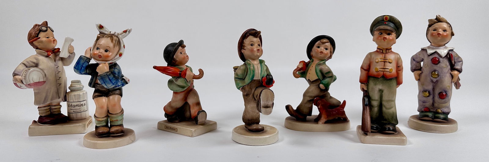 GOEBEL HUMMEL FIGURINE COLLECTION: ESTATE COLLECTION OF GOEBEL HUMMELS. TWO GENERATIONS OF MARKS 1960-72. INCLUDES: SOLDIER BOY, BOY WITH TOOTHACHE, CARNIVAL, LITTLE PHARMACIST, MERRY WANDERER, STROLLING ALONG, GLOBE TROTTER. TALLEST 6