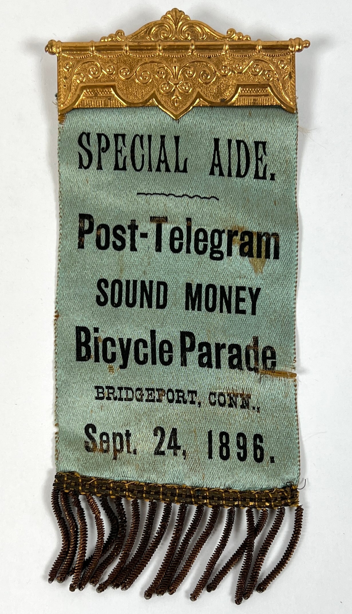 1896 BICYCLE PARADE RIBBON: FEIRABEND BANNERS, BADGES AND REGALIAS, BRIDGEPORT, CT. GILT PIN-BACK WITH RIBBON AND TASSLES. 3"X6"