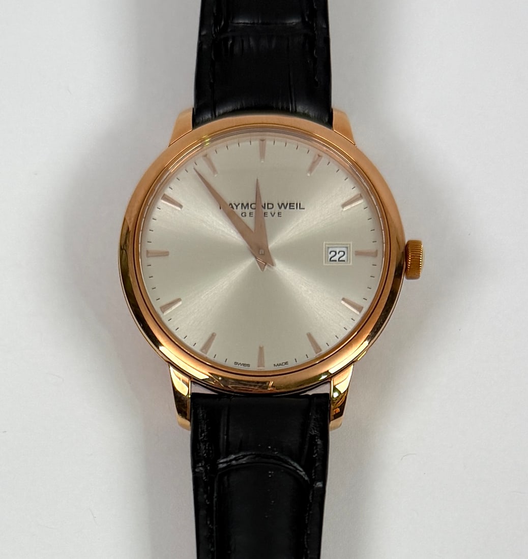 RAYMOND WEIL TOCATTA WATCH: 18K ROSE GOLD CASE. MEN'S WATCH. CASE MARKED 5488-X036774. SWISS MADE, SILVER DIAL, DATE FEATURE, SAPPHIRE CRYSTAL. W/R TO 50M. 39MM. MFG. BLACK LEATHER STRAP. RUNNING