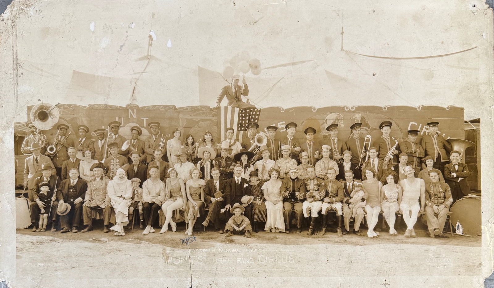 EDWARD J. KELTY HUNT'S CIRCUS PHOTOGRAPH: EDWARD J. KELTY (AMERICAN, 1888-1967) PHOTOGRAPH OF HUNT'S THREE RING CIRCUS, PORT RICHMOND, N.Y., 1932. PANORAMIC PHOTOGRAPH OF CIRCUS OWNERS AND CAST GATHERED IN FRONT OF TRUCK SHOW WAGONS. 
