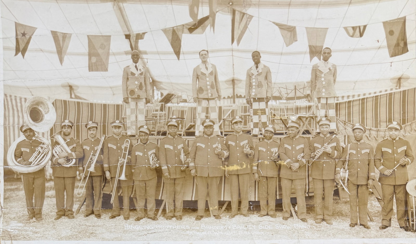 EDWARD J. KELTY CIRCUS PHOTOGRAPH - RBBB CIRCUS: EDWARD J. KELTY (AMERICAN, 1888-1967) PHOTOGRAPH OF THE RINGLING BROS. AND BARNUM & BAILEY CIRCUS SIDESHOW BAND. PANORAMIC PHOTOGRAPH OF SIDESHOW BAND AND PERFORMERS. DOUBLE INK STAMP ON VERSO. 