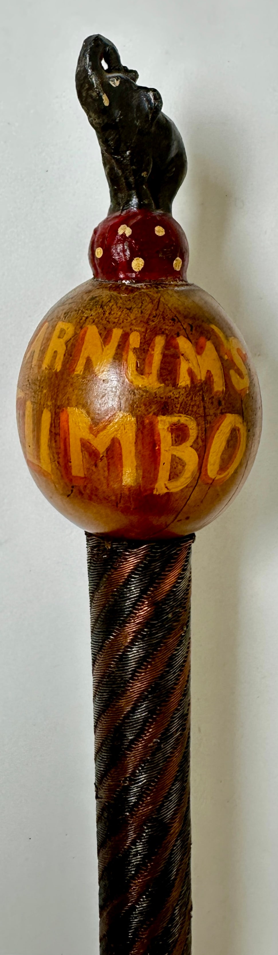 P.T. BARNUM JUMBO SOUVENIR WALKING STICK: CAST METAL ELEPHANT ON BALL TOPPER; WOODEN, HAND-PAINTED BALL-FORM HANDLE; BRAIDED WIRE SHAFT. 38.5"