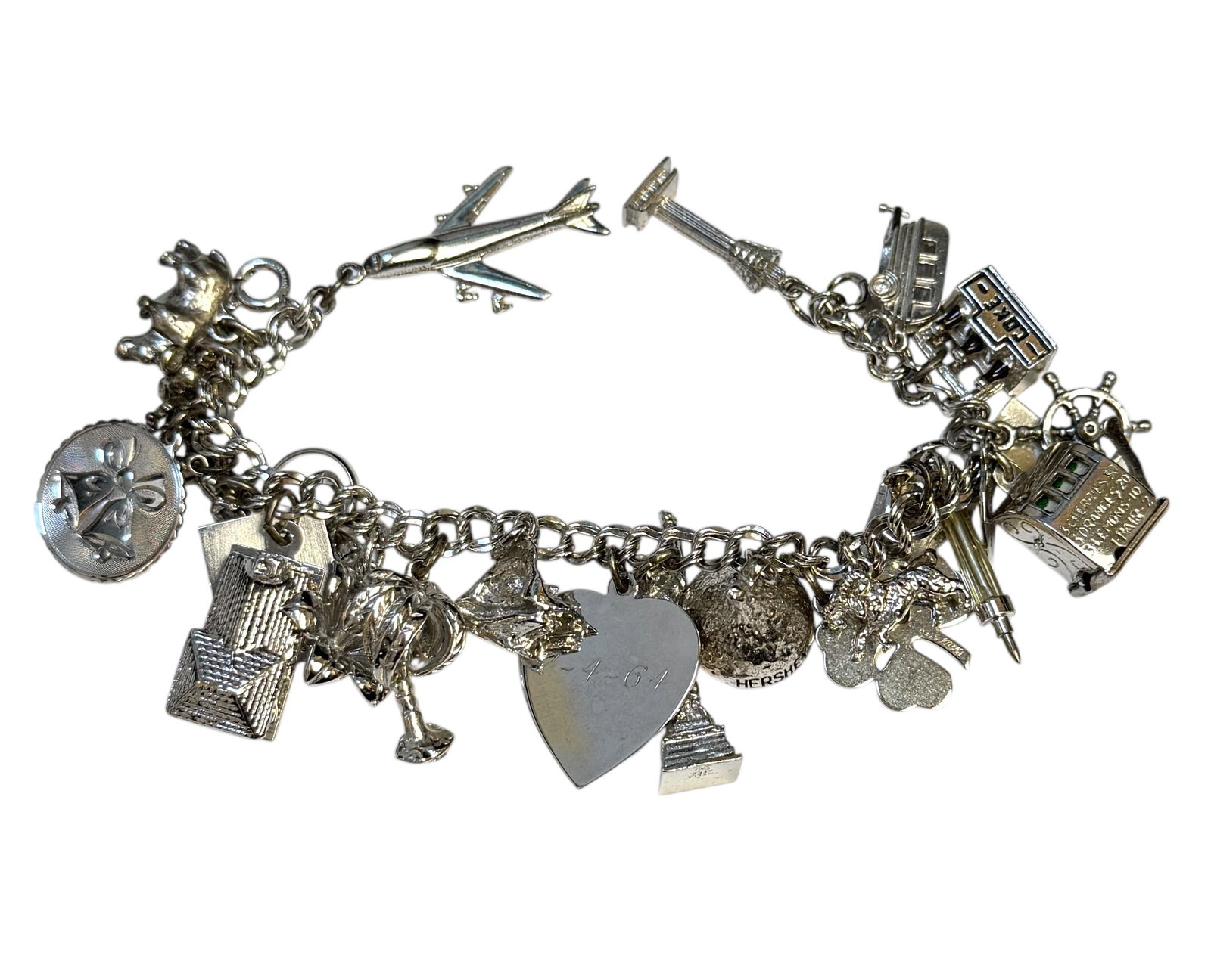 SILVER CHARM BRACELET: CHARM BRACELET WITH OVER TWENTY CHARMS. SOME MARKED STERLING SILVER. TOTAL WEIGHT AS SHOW IS 78 GRAMS.