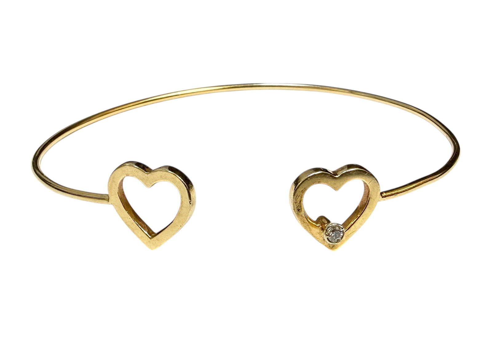 GOLD BANGLE HEART BRACELET: 14K YELLOW GOLD WITH OPEN HEART DESIGN, INTERLOCKING DIAMOND ACCENT PIN. 6.8 GRAMS TOTAL WEIGHT.