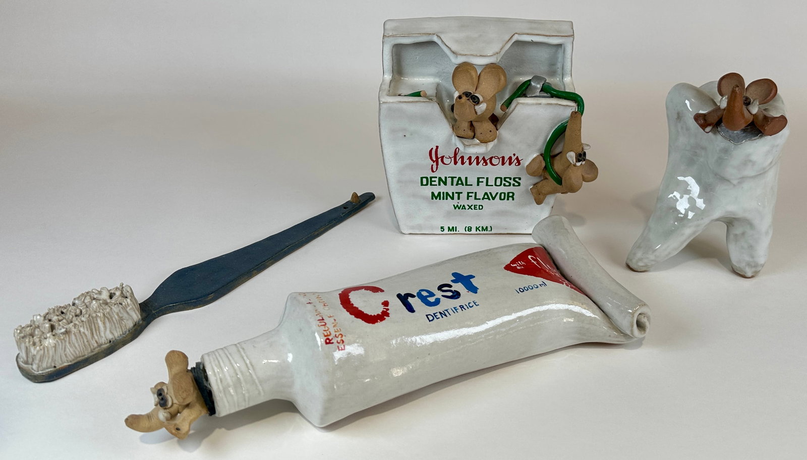 GROUPING OF DENTAL/DENTIST DECORATIVES: DECORATIVE POTTERY SIGNED ATWOOD. TOOTH, FLOSS, TOOTHPASTE TUBE, BRUSH. FLOSS WITH SCATTERED LOSS (FRAGMENTS INCLUDED). TOOTHPASTE TUBE STOPPER LOOSE. TUBE IS 15"L
