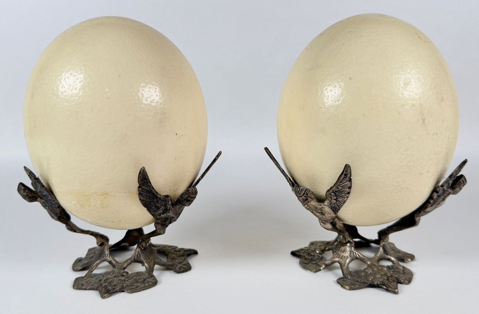 PAIR OF OSTRICH EGGS ON STANDS: LARGE OSTRICH EGGS ON CHERUB BASES. 8"H