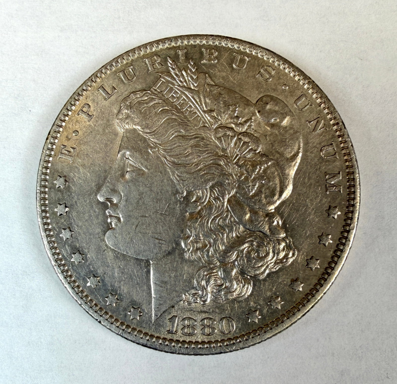 1880-O MORGAN SILVER DOLLAR: AU SLIDER WITH TONING ON THE REVERSE.