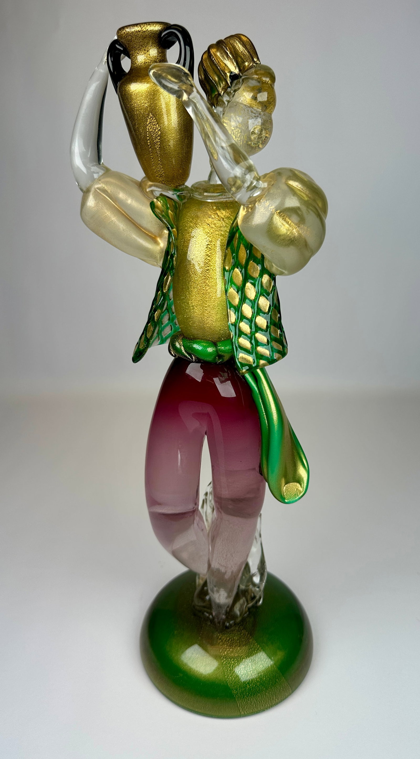 MURANO ART GLASS FIGURAL SCULPTURE: UNSIGNED. MAN WITH WATER PITCHER IN GREEN AND PINK GLASS WITH AUBERGINE WITH GOLD AVENTURINE PITCHER. 17"H. REPAIR AT SASH. CONDITION REPORT AVAILABLE ON REQUEST. CANNOT ISSUE REPORTS WHILE AUCTION IS