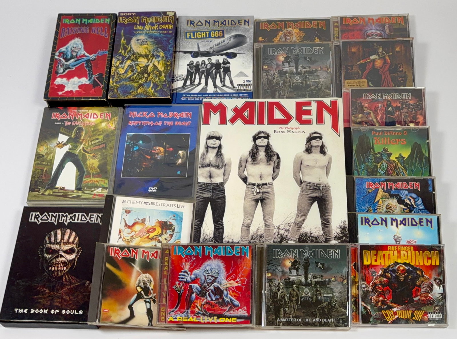 IRON MAIDEN MEMORABILIA: VHS INCLUDING: 1993 RAISING HELL, 1985 LIVE AFTER DEATH. ASSORTMENT OF COMPACT DISCS AND DVDS. IRON MAIDEN - A PHOTO HISTORY BY ROSS HALFIN