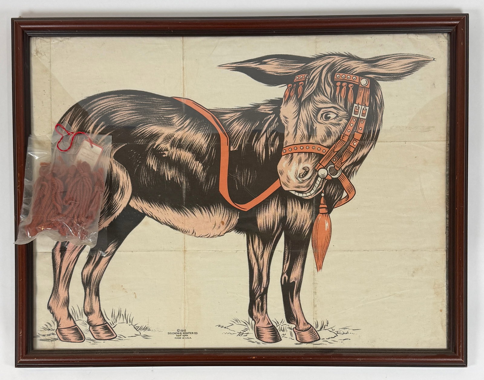 1916 SELCHOW & RIGHTER CO. PIN-THE-TAIL ON THE DONKEY: ANTIQUE CHILDREN'S GAME. FRAMED CANVAS DONKEY AND BAG OF YARN TAILS. 19"X25"