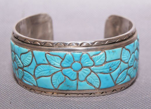 ZUNI SILVER BRACELET: 1970s channel inlaid turquoise with carved floral design by Nicholas Leekela , 5" x 1" x 1" Shipping charge are for the United States. The shipping on this lot is $10.00. Outside the United States the
