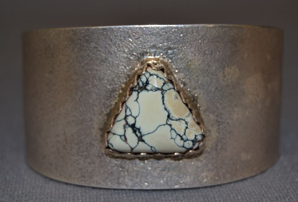SANTO DOMINGO SILVER BRACELET: contemporary sterling silver tufus cast and single white turquoise stone design on inside signed for Gilbert Dino Garcia 5.25"x1.5"x1.25" Shipping charge are for the continental United States only The