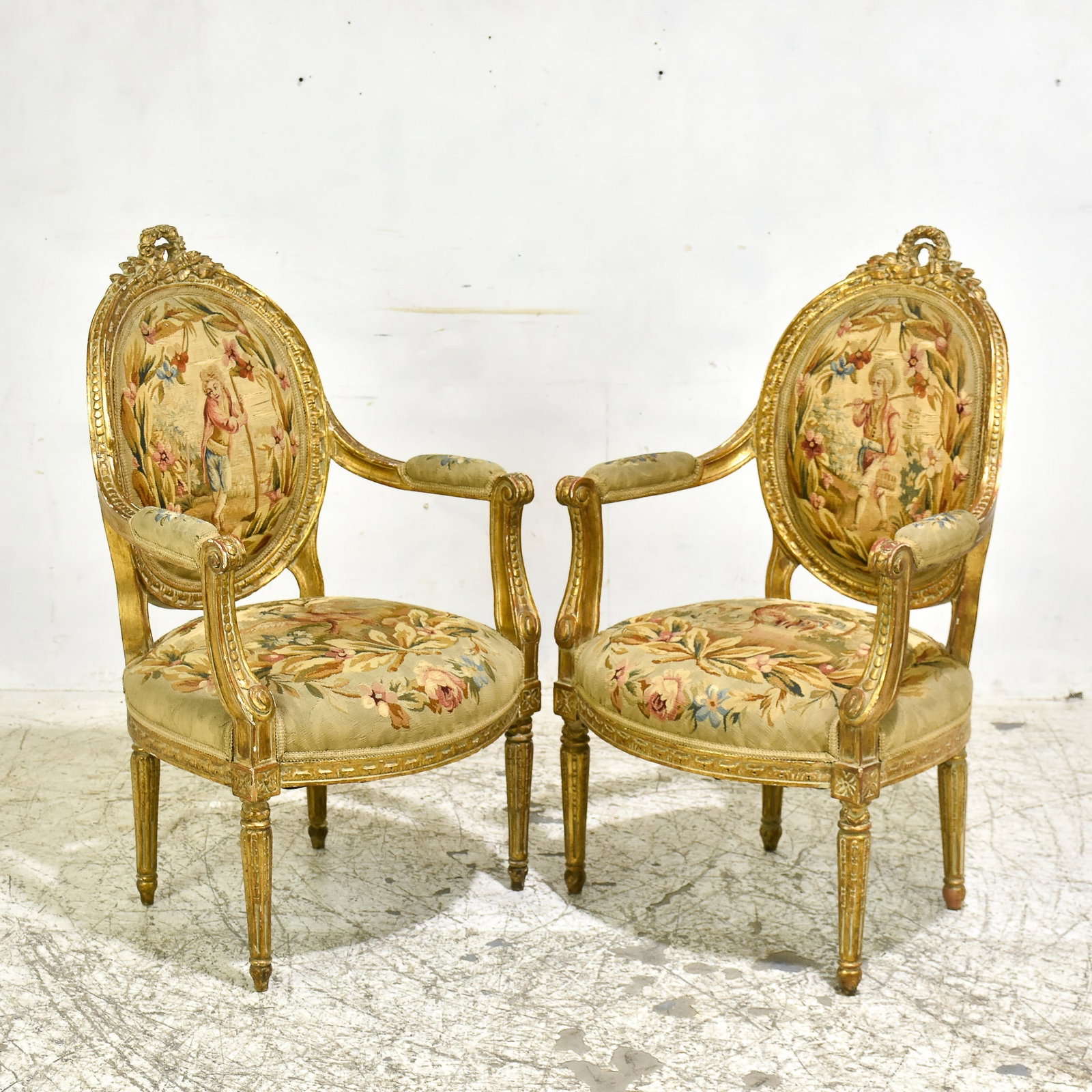 Pair of Louis XVI Style Giltwood Fauteuils: * (41” h x 24 1/2” w x 20 1/2” d) Losses to gilding, wear to upholstery