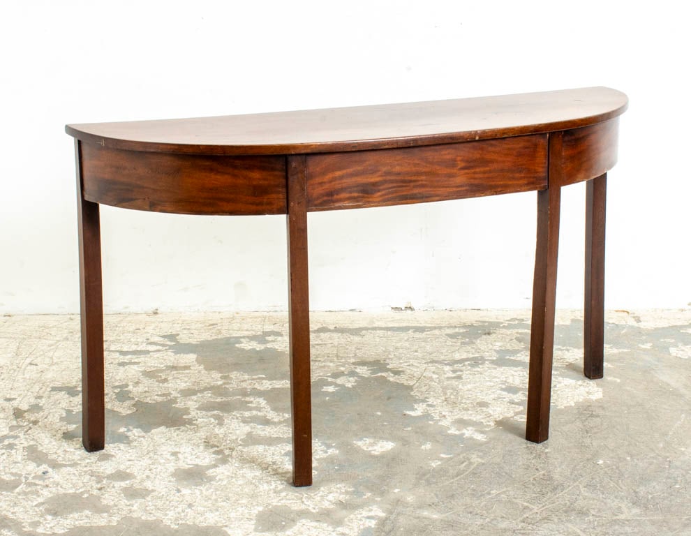 George III Mahogany Demilune Table: Late 18th century . (29" h x 52 1/2" w x 17 3/8" d) Stains to top, wear to edges, legs possibly replaced