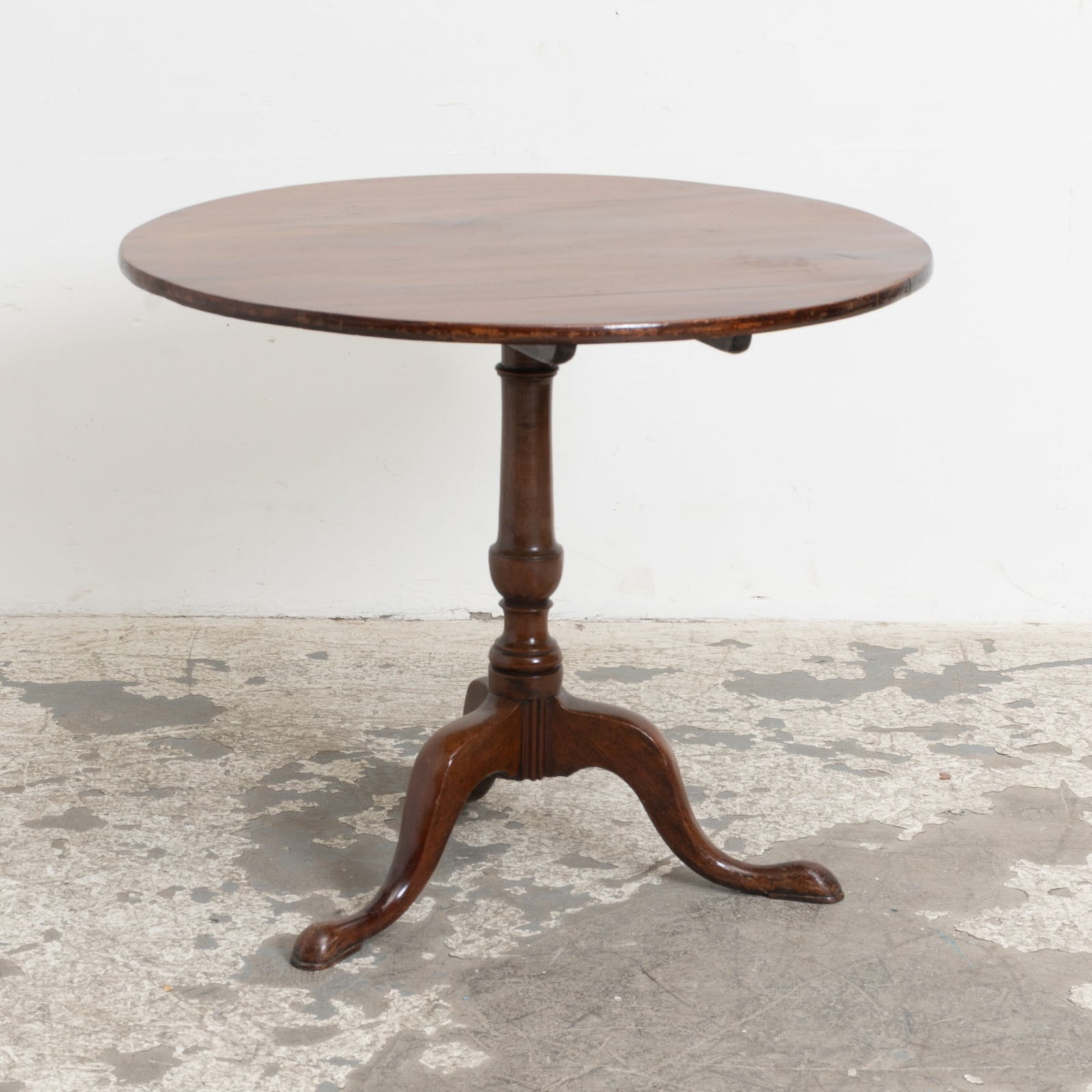 Chippendale Mahogany Tilt-Top Table: - (27 1/2" h x 32" dia) edgewear and scratches to top; repairs to two feet, one of which now has an old wooden brace; plugged holes to stem; cracking to tilt-top mechanism; sunfading to top; old marks