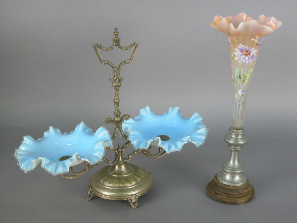 (2) Epergnes including a trumpet-form vase: of peach glass with ruffle rim and enamel floral decoration on a wood and pewter base - 14.75"H; and a 14" epergne with two ruffle rim blue opaque glass inserts on a silver over brass stand with scrol