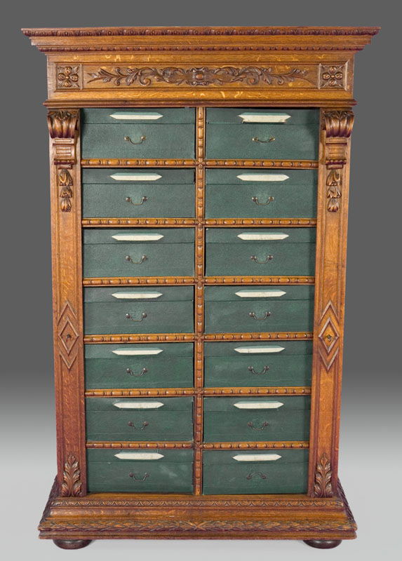 Victorian carved oak side locking file cabinet,: Victorian carved oak side locking file cabinet, the carved cornice over a floral carved frieze with (14) green cloth covered cardboard drawers below, flanked by flat pilasters with applied carvings wh