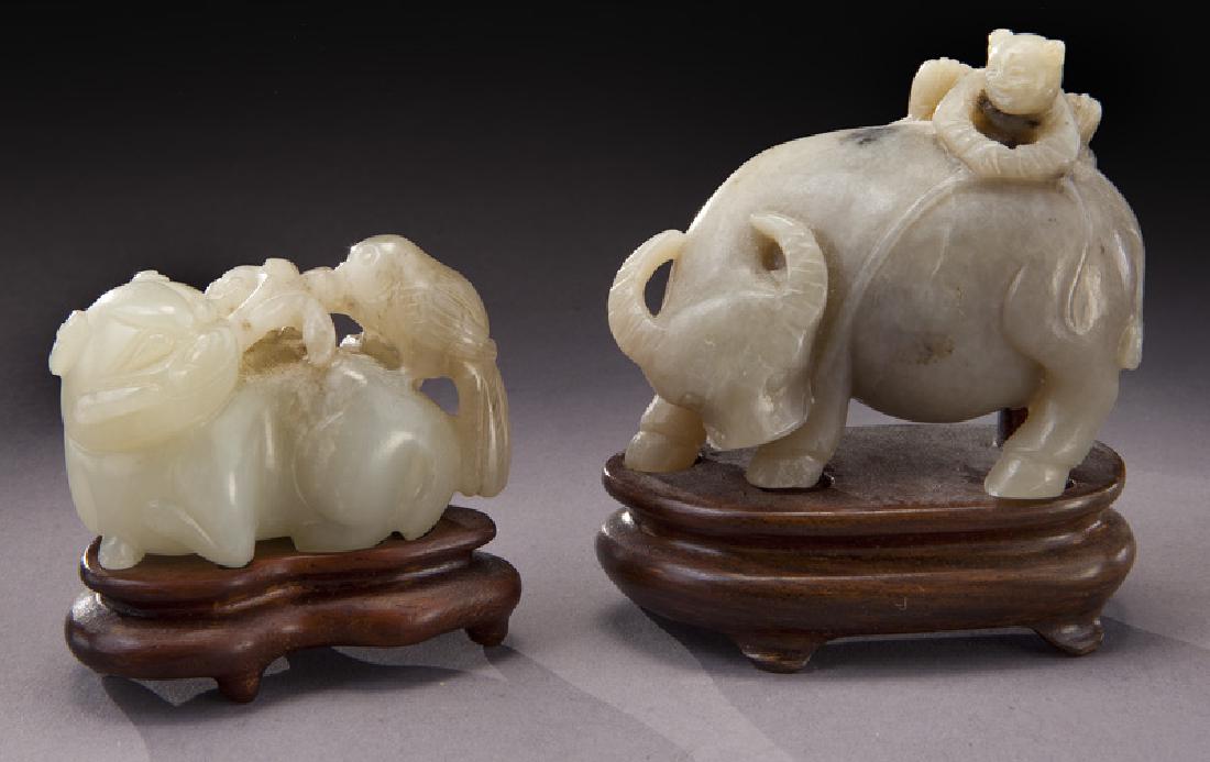 (2) Chinese Qing carved jade toggles,: (2) Chinese Qing carved jade toggles, depicting a cat with a bird and a water buffalo with a boy. Largest: 2"H x 2.25"L, Circa - 18th - 19th C.