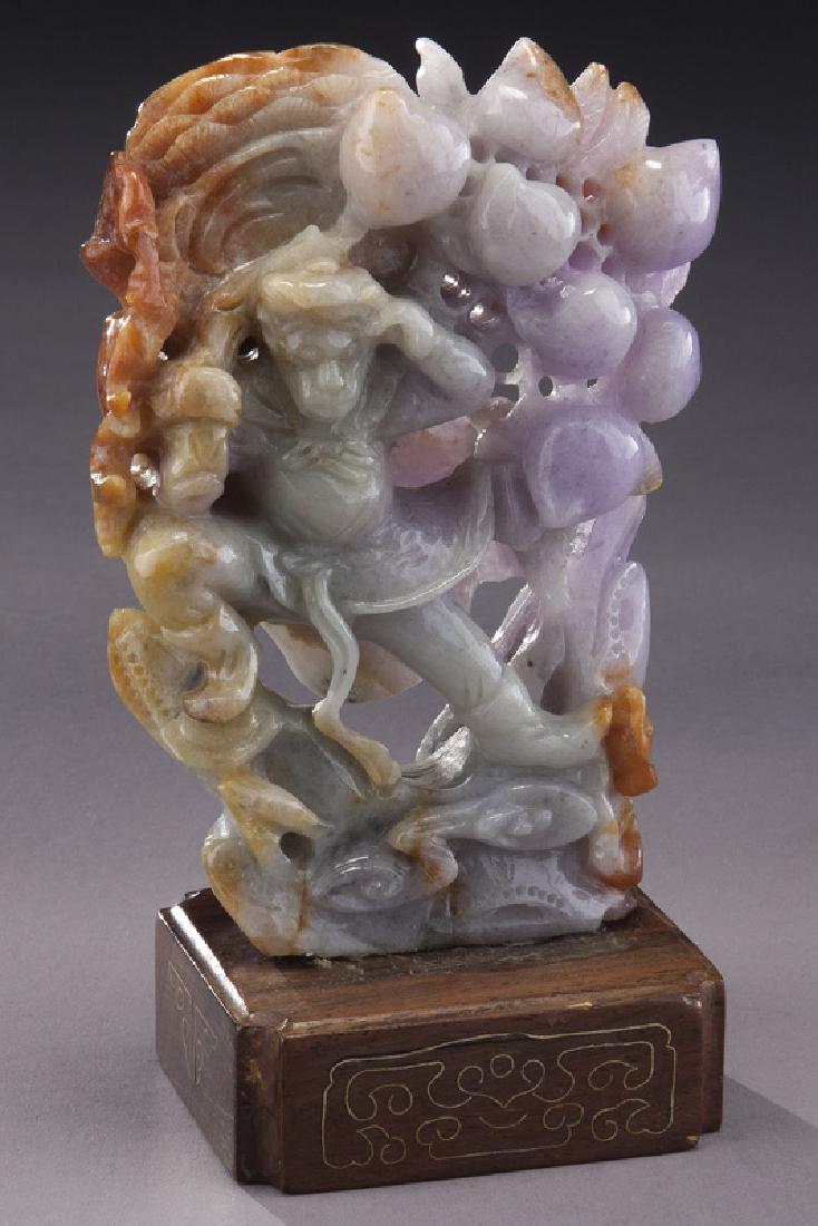Chinese lavender jadeite figural carving: Chinese lavender jadeite figural carving on wood base, depicting a costumed monkey and peach tree. Jade: 5.5"H x 3.5"W; Overall: 6"H. Circa - 20th C.