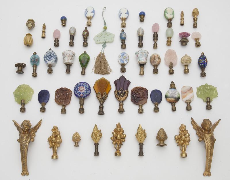 Collection of (48) lamp finials,: Collection of (48) lamp finials, including: jade, porcelain, cloisonne, gilt bronze, etc., plus two winged figural gilt bronze furniture mounts and one jade toggle. Circa - 1900 -1950.