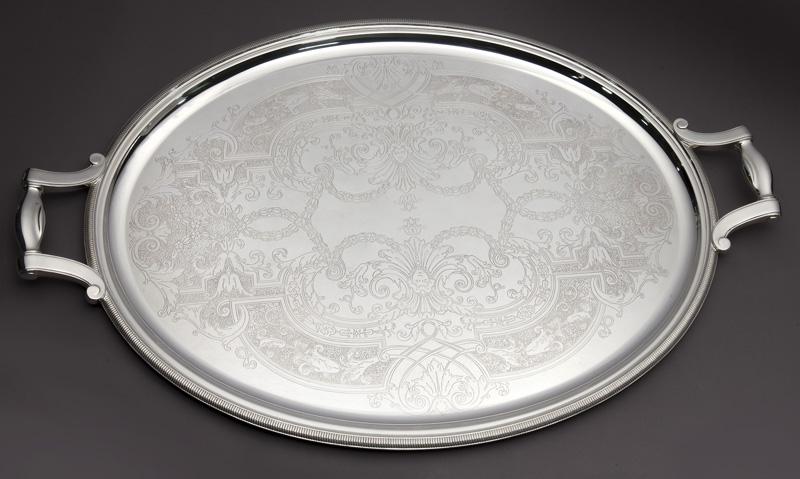 Christofle oval silverplated 2-handle serving tray: Christofle oval silverplated 2-handle serving tray with elaborate engraving. With original Christofle cardboard box and silver bag. 24.75"L x 16.5"W, Circa - 20th C.