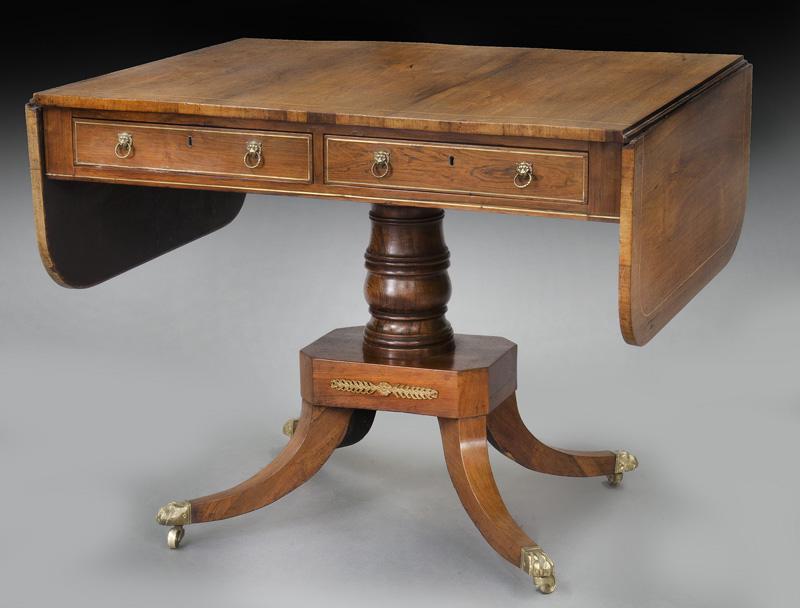 Regency faded mahogany sofa table of rectangular: Regency faded mahogany sofa table of rectangular form with two drop leaves with rounded corners over two drawers, standing on a turned column on platform with four splayed legs having brass paw feet a