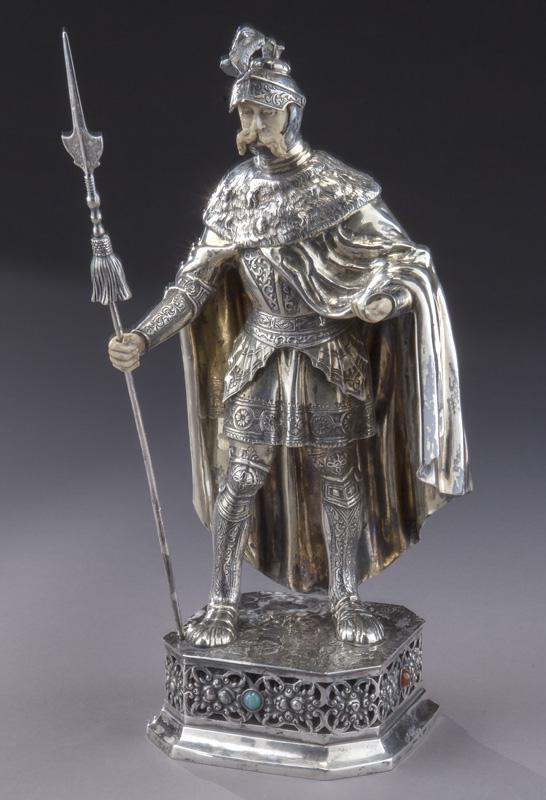 Sterling silver figure of a Knight wearing: Sterling silver figure of a Knight wearing a cape and helmet, holding a spear and standing on a reticulated plinth set with semi-precious stones. Hands and face of carved bone. Stamped on base, "Sterl