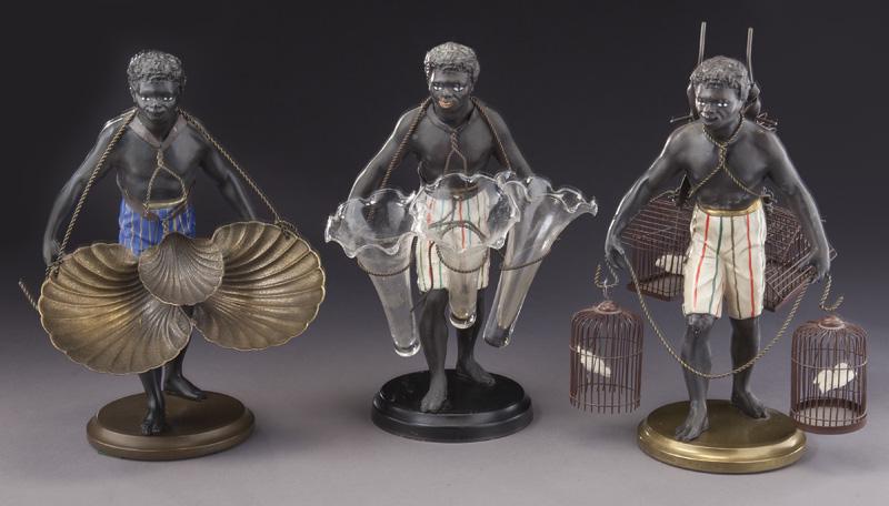 (3) Continental polychrome & patinated metal: (3) Continental polychrome & patinated metal blackamoor epergnes: (1) carrying three shell-form trays; (1) with three glass vases; (1) with five bird cages. Each raised on a circular base. Tallest: 15