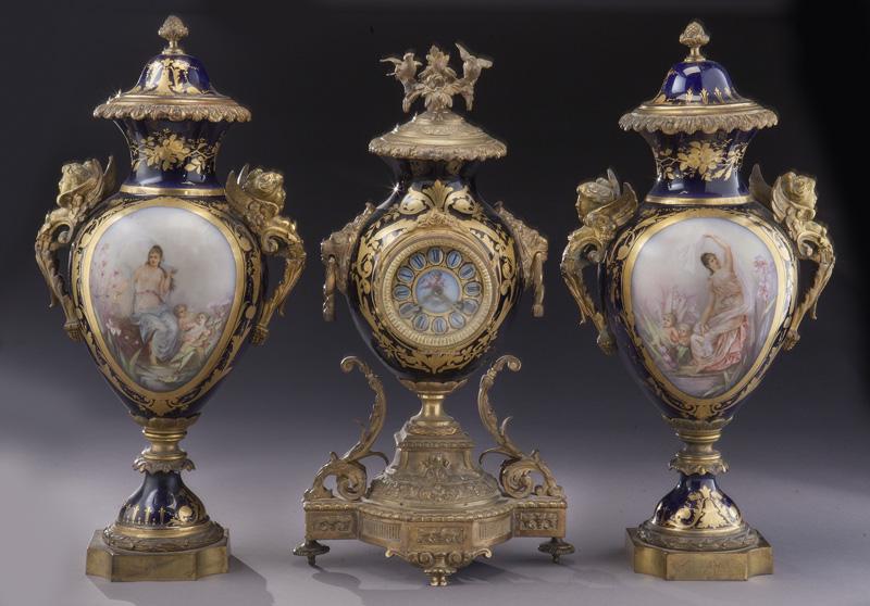 (3) Pc. Sevres-style garniture set,: (3) Pc. Sevres-style garniture set, including: (1) central clock and (2) urns with classical figural medallions to cobalt ground, raised on canted corner gilt bronze bases. Reserves signed, "C. Caillu