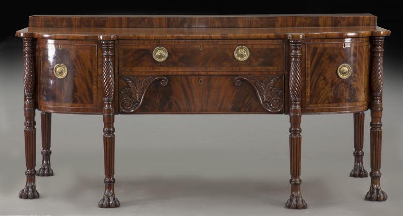 Irish Georgian period mahogany sideboard,: Irish Georgian period mahogany sideboard, the shaped top over conforming base with two central long drawers flanked by doors, raised on turned and fluted legs ending in paw feet. 38.5"H x 80.25"W x 34