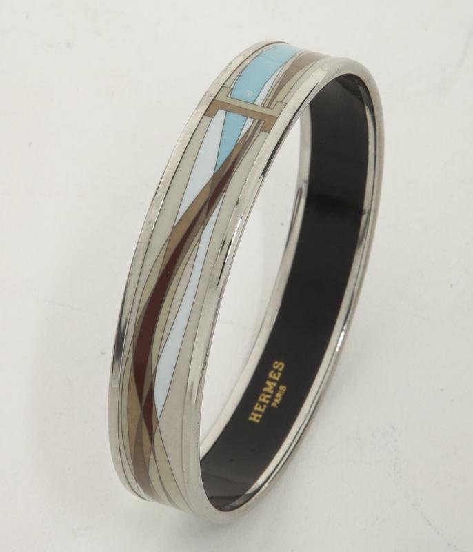 Hermes Enamel Bangle Bracelet: Hermes Enamel Bangle Bracelet in beige/white/light blue stainless steel without nickel long ribbon motif and silver hardware, marked: stamp H. Includes: box. 2.25 x .5" Dia.
