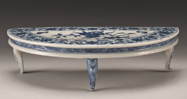 Chinese Qing dynasty blue and white porcelain: demi-lune stand finely painted to depict peonies, bats and peach trees, the symbols of prosperity, happiness any longevity. Six character Qianlong mark in blue underglaze. 2.75"H x 10.75"W x 5.5"D, Ci