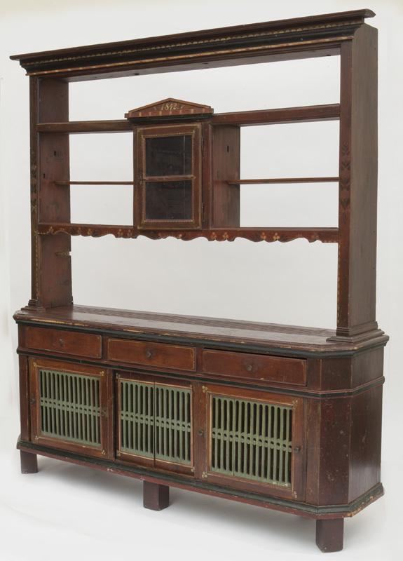 Continental painted pine kitchen dresser,: the molded cornice over upper rack with central cupboard having painted decoration and dated "1842", above a canted corner base having three short drawers over sliding doors. PROVENANCE: From the Vivi