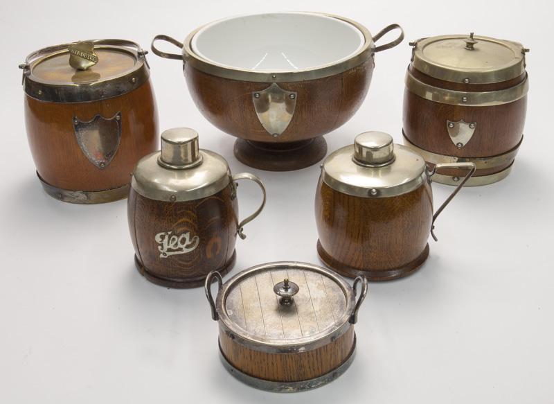 (6) English silverplate and oak table articles,: including: (1) wine cooler; (1) lidded biscuit jar; (1) lidded tea caddy; (1) sugar; (2) tea canisters. PROVENANCE: From the Vivian Young and Lady Primrose's Collection, Dallas, TX. Cooler: 12" over h