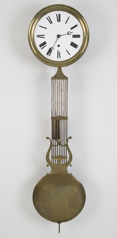 French regulator type wall clock with 11" Dia.: white porcelain dial surrounded by brass bezel and large heavy brass gridiron pendulum. The heavy brass 1-weight, time only movement with pin wheel escapement and sweep seconds hand (hand missing). 14