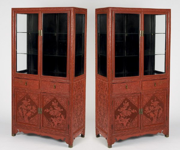 Pr. Chinese cinnabar curio cabinets: the top panels with greek key borders, the lower panels carved with peony decoration. Provenance: The collection of Derrill Osborn. 70"H x 35"W x 18"D, Circa - 20th C.
