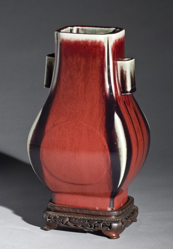 Chinese Qing Guangxu Imperial Ox-blood porcelain va: Chinese Qing Guangxu Imperial Ox-blood porcelain vase raised on a rosewood stand, having a six character mark on the bottom. There is a hole drilled in the bottom of the vase. 12"H x 7.5"W x 6.5"D,